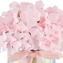 Close-up of pink hydrangea blooms with pale pink ribbon around an iridescent pot