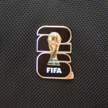 Enamel lapel pin featuring FIFA trophy emblem on dark fabric