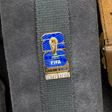 Enamel lapel pin featuring FIFA logo with United States label on gray fabric