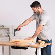 Electric screwdriver drilling into a wooden board on a workbench