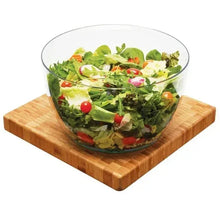Salad spinner bowl with salad greens, tomatoes, and herbs on wooden base