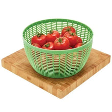 Salad spinner basket with tomatoes on wooden base, green draining grid