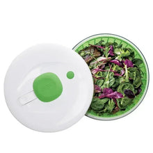 Salad spinner lid with green pump button and clear bowl filled with leafy greens
