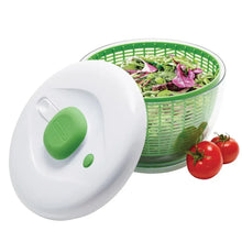 Salad spinner with white lid partly open over green basket and leafy greens and tomatoes