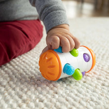 White sensory roller rattle toy with orange end, blue wheel, and green and purple pegs
