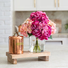 Faux hydrangea arrangement in clear vase with bright pink and pale peach blooms