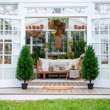 Faux cedar topiary trees in black pots, styled on a patio near outdoor sofa