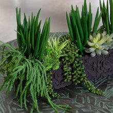 Faux succulent arrangement close-up with dark textured planter and layered green leaves