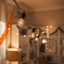 Indoor cafe string lights with warm clear globe bulbs on black hanging wire