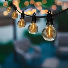 Cafe string lights with clear globe bulbs on black cord glowing warm white