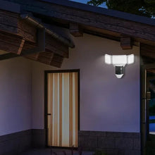 Exterior smart flood light camera on wall with three illuminated LED panels and lens area
