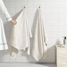 Cream bath towel set, two towels hanging on wall hooks