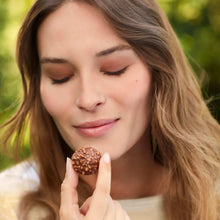 Milk chocolate hazelnut candy in hand, gold wrapper and chocolate shell