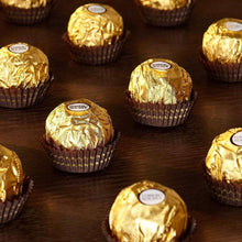 Gold-wrapped Ferrero Rocher milk chocolate hazelnut candies in foil cups on dark surface