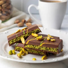 Milk chocolate pistachio bars on plate with chopped pistachios.