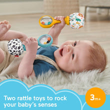Baby reaching for rattle maracas, yellow-handle one with animal-print ball.