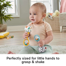 Baby holding two rattle maracas with blue and yellow handles and patterned balls.