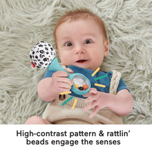 Baby holding a rattle maraca with blue handle and black-and-white patterned ball.