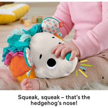 Hedgehog plush sensory toy with baby hands, showing white face, teal accents, and bright belly