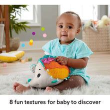 Hedgehog plush sensory toy on the floor with a baby holding it, showing multicolor textures