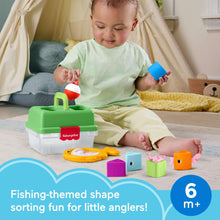 Kid playing with a green Fisher-Price tackle box and colorful shape blocks