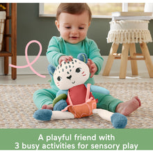 Baby playing with snow leopard sensory plush toy on carpet, teal and orange