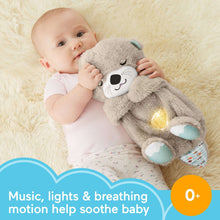 Baby cuddling a gray plush otter sound machine with glowing belly and blue fin pads