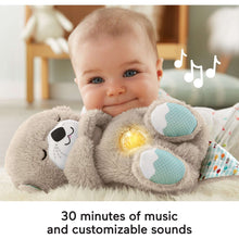 Baby holding a gray plush otter sound machine with glowing belly and blue fin accents