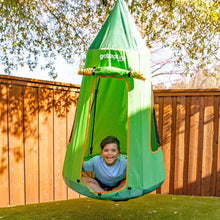 Child in green tree swing tent with orange-trimmed saucer seat, hanging in yard