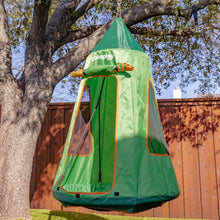 Green tented tree swing with orange trim, hanging from a tree branch outdoors.