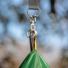 Metal hanging clip and swivel with yellow-orange strap attached to green swing tent fabric.