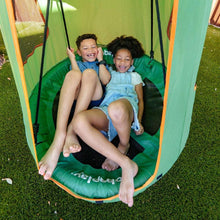 Green tree swing tent with saucer seat, orange trim, kids sitting inside outdoors