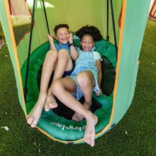 Green saucer swing with tent canopy, orange trim; two children seated inside outdoors.