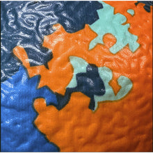 Textured foam dodgeball close-up with blue, orange, and teal map shapes
