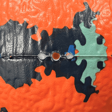 Foam dodgeball close-up seam with orange and blue world-map textures and teal accents