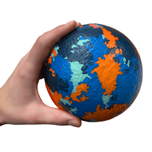 Foam dodgeball with world-map colors held in a hand for easy grip
