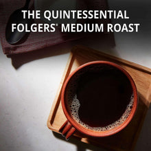 Cup of dark coffee with foam, beside Folgers Medium Roast coffee bag