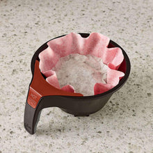Coffee filter basket with pink paper liner and black holder on countertop