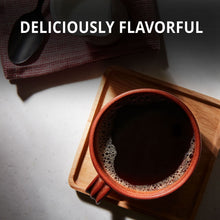 Brewed coffee in a red-rim mug with foam, on a wooden tray.