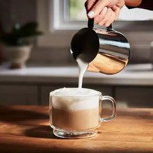 Cup of coffee with dark stream being poured from a spoon