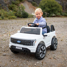 White Ford ride-on truck with black wheels and seated child driver