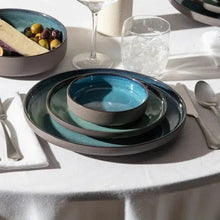 Antiqued flatware with fork and knife beside blue plate in table setting