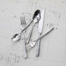 Faceted flatware set arranged with forks, spoon, and knife, polished silver pieces
