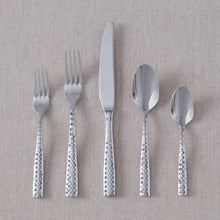 Faceted flatware set arranged: knife, forks, and spoons with textured silver handles