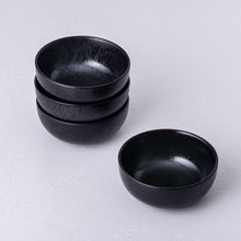 Stacked black bowls with speckled glaze, two sizes shown side by side