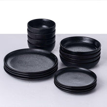 Black speckled dinnerware set with stacked plates and bowls, multiple pieces shown