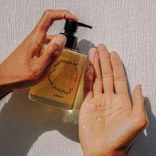 Amber hand soap bottle with pump and foam on hands
