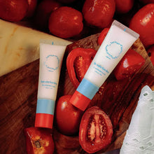Tomato garden hand care tubes with blue caps and labels, beside tomatoes