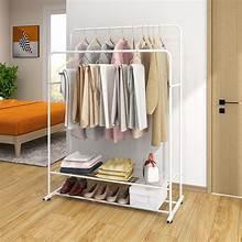 White freestanding garment rack with single rod and wire shelves, hanging shirts and coats