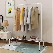 White freestanding garment rack with single rod, hanging coats and shoes on bottom shelf